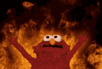 Elmo From Sesame Street Is Standing In Front Of A Fire GIF