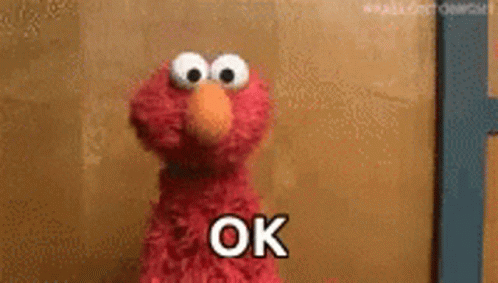 Elmo From Sesame Street Is Standing In Front Of A Wall And Says Ok . GIF