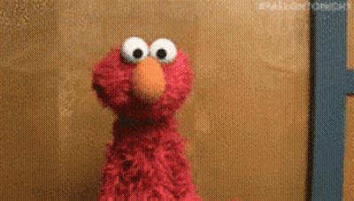 Elmo From Sesame Street Is Standing In Front Of A Wall . GIF