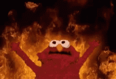 Elmo From Sesame Street Is Standing In Front Of A Wall Of Fire . GIF
