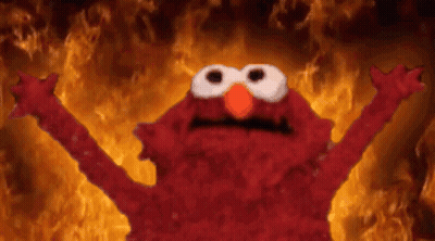 Elmo From Sesame Street Is Standing In Front Of A Wall Of Fire . GIF