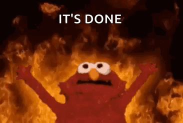 Elmo From Sesame Street Is Standing In Front Of A Wall Of Flames . GIF