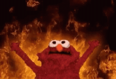 Elmo From Sesame Street Is Standing In Front Of A Wall Of Flames . GIF