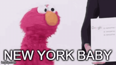 Elmo From Sesame Street Is Standing Next To A Person Holding A Sign That Says New York Baby . GIF