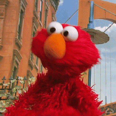 Elmo From Sesame Street Is Standing On A City Street GIF