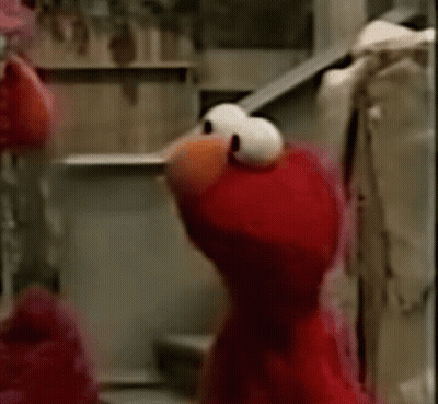 Elmo From Sesame Street Is Standing On A Set Of Stairs And Looking At The Camera . GIF