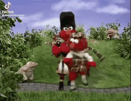 Elmo Is Playing A Bagpipe And Elmo Is Riding Elmo On His Back . GIF