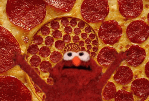 Elmo Is Standing In Front Of A Pizza Covered In Pepperoni GIF
