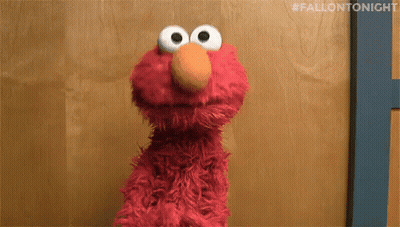 Elmo The Sesame Street Character Is Standing In Front Of A Wooden Wall . GIF
