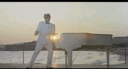 Elton John Standing Beside White Piano GIF