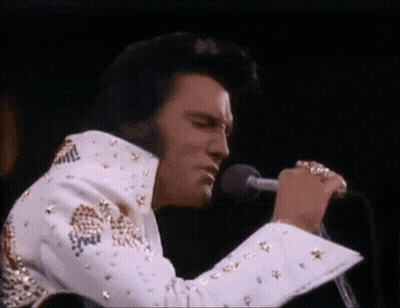 Elvis Presley Is Singing Into A Microphone While Wearing A White And Gold Suit . GIF