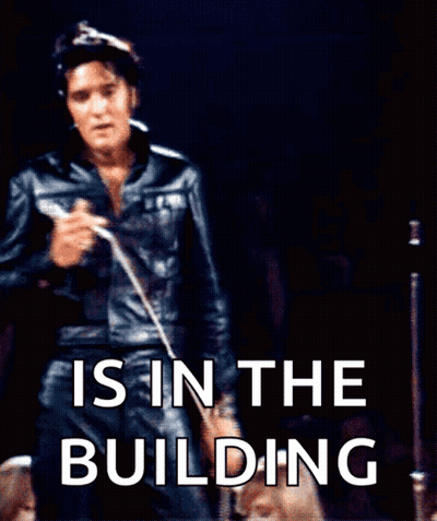 Elvis Presley Singing Into A Microphone With The Words " Is In The Building " Behind Him GIF