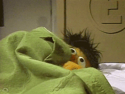 Ernie From Sesame Street Is Laying In Bed With A Green Blanket GIF