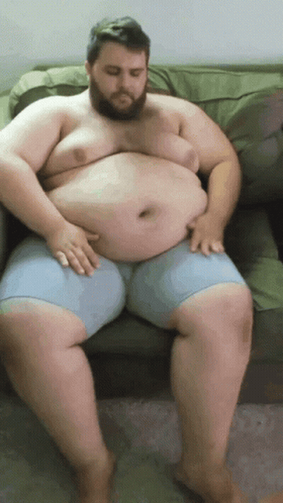Fat Man Sitting On Couch Hands On Belly GIF