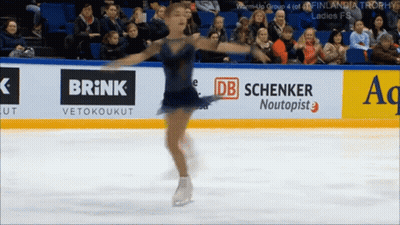 Female Figure Skater Performing In Front Of Brick Banner GIF