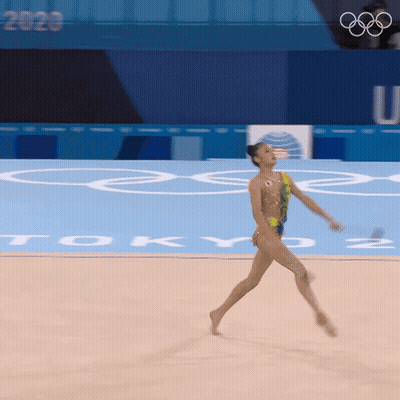 Female Gymnast Performing In Front Of Tokyo Sign GIF