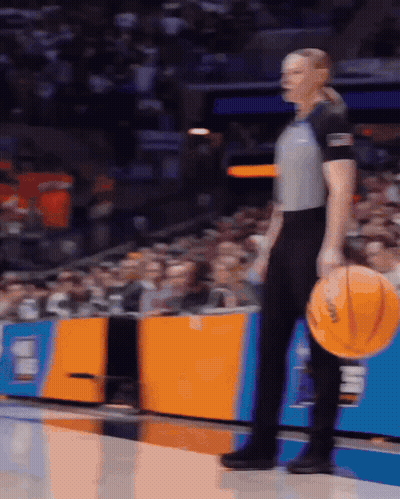 Female Referee Holding Basketball In Front Of Crowd GIF