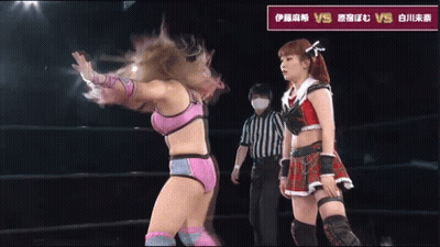 Female Wrestler Next To Wrestler In Red Pants With X On Pocket GIF