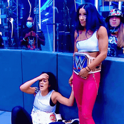 Female Wrestler Standing Beside Sitting Wrestler GIF