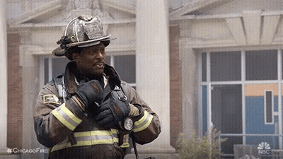 Firefighter Standing In Front Of Building With Gloves And Helmet GIF