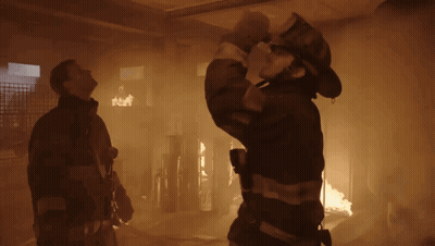 Fireman Holding Hose In Front Of Burning Building GIF