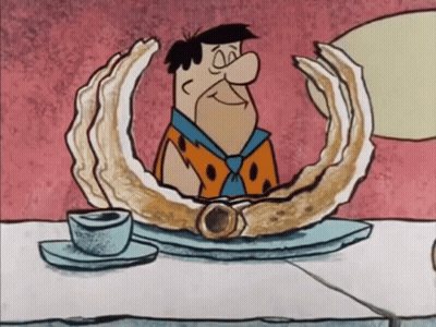 Flintstone Sitting At Table With Oyster GIF