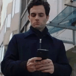 Focused Joe Goldberg Holding Cellphone GIF