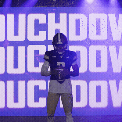 Football Player Holding Ball In Front Of Duchov Sign GIF