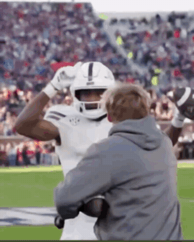 Football Player In Helmet Held By Coach GIF