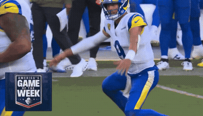 Football Player Kneeling in Front of Game of the Week Sign