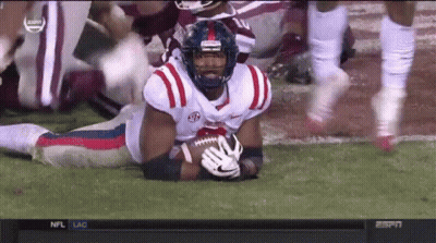 Football Player Lying On Field Holding Ball With NC Helmet GIF
