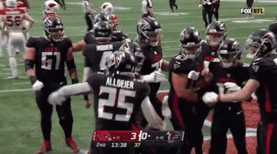 Football Player Number 25 Surrounded By Teammates GIF