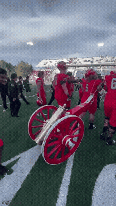 Football Players Holding Cannon On Field GIF