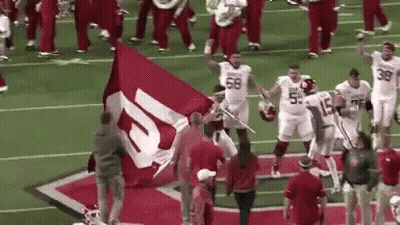 Football Players Holding Large Red And White Flag GIF