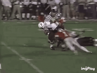 Football Players Playing On Field With One Laying Down GIF