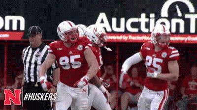 Football Players Standing In Front Of Auction Sign GIF