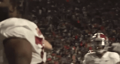 Football Players Standing On Field Holding Football GIF