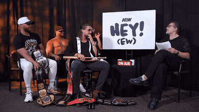 Four Men Sitting In Front Of Hey (Ew) Sign GIF