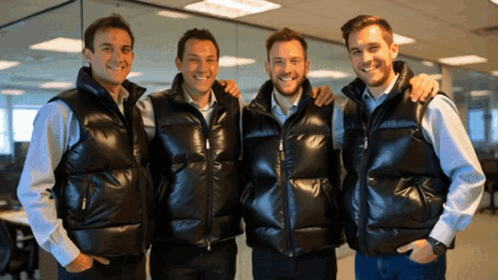 Four Men Wearing Black Vests Are Posing For A Picture Together GIF