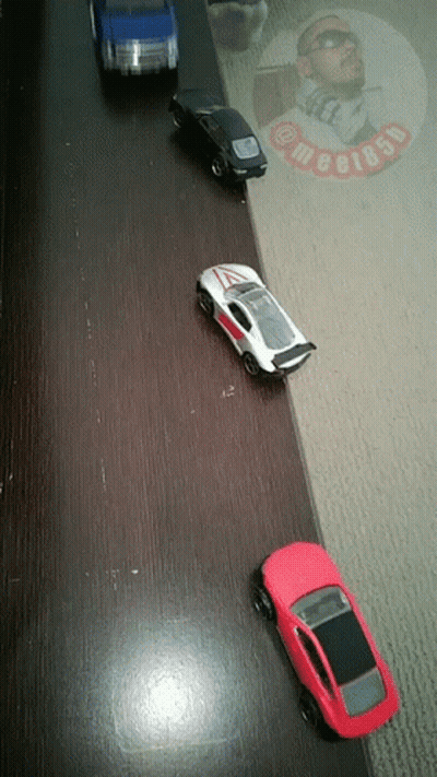 Four Toy Cars Lined Up With Man In Sunglasses And Text Megi85p GIF