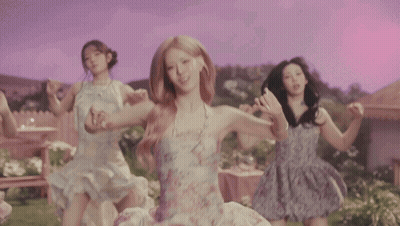 Four Women Are Dancing In Front Of A House In A Garden GIF