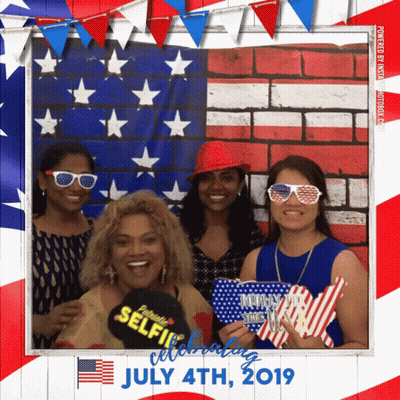 Four Women Pose For A Picture In Front Of An American Flag On July 4Th 2019 GIF