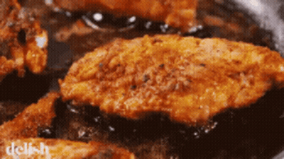 Fried Chicken Is Being Cooked In A Frying Pan With The Word Delish In The Corner GIF