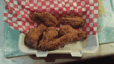 Fried Chicken Wings In A Styrofoam Container On A Checkered Paper GIF