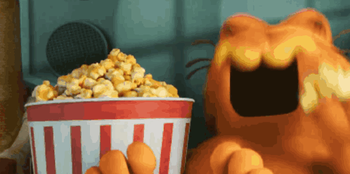 Garfield Is Eating A Bucket Of Popcorn With His Mouth Open GIF