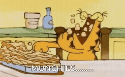Garfield Is Sitting At A Table Eating A Piece Of Lasagna . GIF