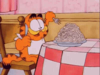 Garfield Is Sitting At A Table With A Plate Of Spaghetti On It . GIF