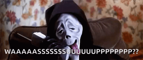 Ghostface Is Sitting On A Couch Talking On A Cell Phone . GIF