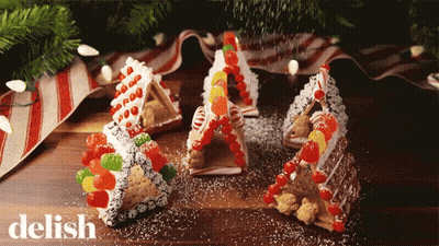 Gingerbread Houses Made Out Of Graham Crackers And Candy Are On A Table With The Word Delish In The Corner GIF