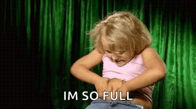 Girl Holding Stomach In Front Of Green Curtain GIF